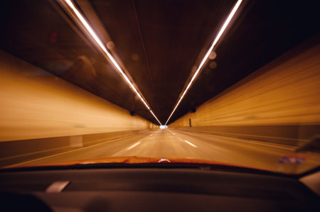 Perspective view from the car at the long orange tunnel with end at the end - fast transportation in modern futuristic cityの写真素材