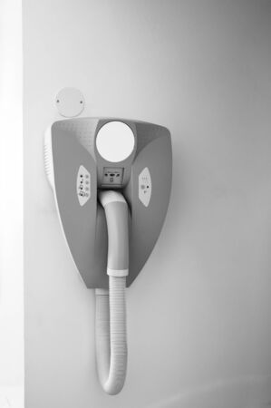 Black and white image of hairdryer hanged on the wall of bathroom in modern hotel with power plug for the razor machine - black and white image.の写真素材