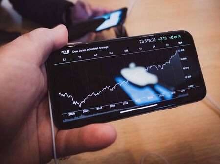 Paris, France - Nov 3, 2017: latest professional iPhone smartphone manufactured by Apple Computers with DJI Dow Jones Industrial stock index Apple Logo reflected in screenのeditorial素材