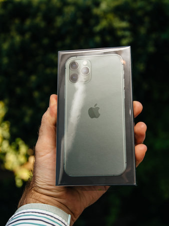 Paris, France - Sep 20, 2019: Man hand holding front cardboard box with new green iPhone 11 Pro Max...