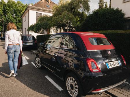PAris, France - Jul 26, 2017: Elegant woman leaving leaving her Fiat 500 mini cabrio car with red...
