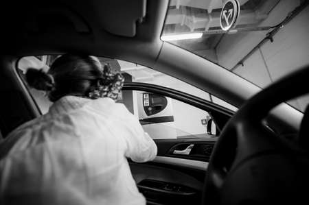 Paris, France - Jul 14, 2011: Rear view of woman paying at the vending car parking barrier gate - view from inside the car black and white imageのeditorial素材