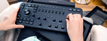 Paris, France - Spe 13, 2019: overhead view of female video editor vlogger retoucher woman holding unboxing operating new Loupedeck Plus photo and video editing console