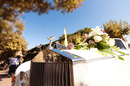 Paris, France - Sep 21, 2019: Low angle view of silver grille of Luxury Rolls-Royce British luxury car logotype with the Spirit of Ecstasy bonnet ornament and flowers on the hoodのeditorial素材