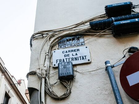 Barcelona, Spain - Nov 16 2017: Low angle view of Carrer de la Fraternitat street name translated as Street of Fraternity and multiple cables for internet and electricityのeditorial素材
