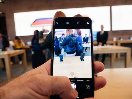 Paris, France - Nov 3, 2017: Customers admiring inside Apple Store the latest professional iPhone smartphone manufactured by Apple Computers taking a picture with the camera appのeditorial素材