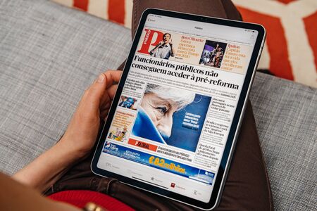 Paris, France - Jun 2, 2019: Man or woman hand holding Ipad tablet reading the electronic version of Portuguese Publico newspaper about daily news in Portugal and Brexit on Apple news appのeditorial素材