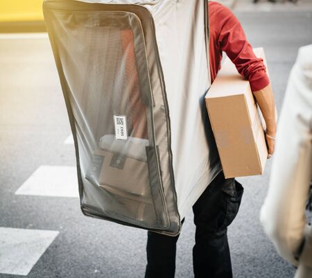 Barcelona, Spain - Nov 17, 2017: Working man holding carton box and carrying extra-large see-through delivery bag on his back with Amazon packages and boxesのeditorial素材