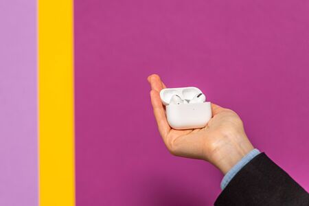 Paris, France - Oct 30, 2019: Woman showing the new open charging case unboxing new Apple Computers AirPods Pro headphones with Active Noise Cancellation for immersive sound yellow purple tech backgroundのeditorial素材