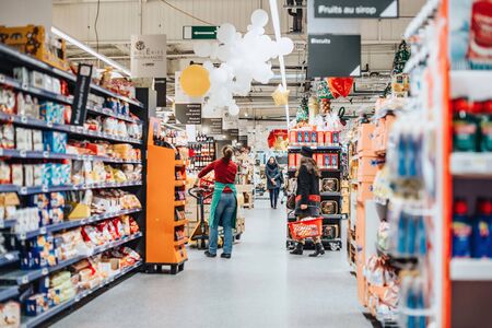 Strasbourg, France - Dec 21, 2016: Interior of large French Auchan supermarkets with worker preparing goods to be arranged on the shelves and customers shoppingのeditorial素材