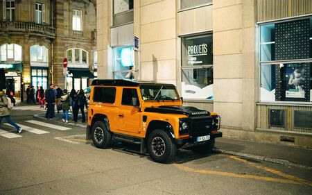 Strasbourg, France - Nov 23, 2017: Side view of luxury orange colored Range Rover Defender SUV parked on French street pedestrians in backgroundのeditorial素材
