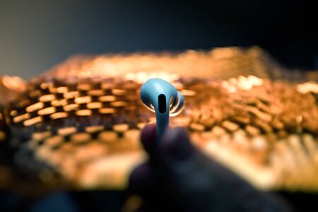 Paris, France - Oct 30, 2019: Man hand holding against abstract background futurstic new Apple Computers AirPods Pro headphones with Active Noise Cancellation for immersive soundのeditorial素材