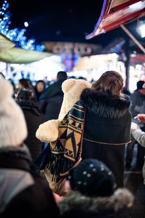 Strasbourg, France - Dec 20, 2016: Rear view of young woman carrying large white bear toy between market stalls of annual Christmas Market in Strasbourgのeditorial素材