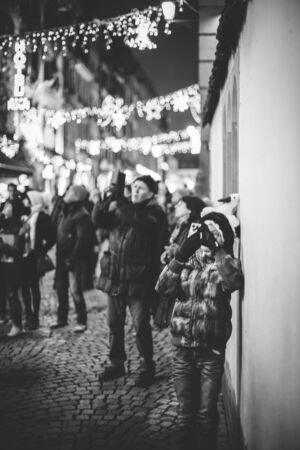 Strasbourg, France - Dec 20, 2016: French street with woman taking photograph on the smartphone of the busy Rue du Maroquin decorated illuminations bokeh for Christmas Marketのeditorial素材