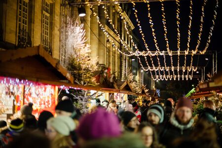 Strasbourg, France - Dec 20, 2016: Large crowd of people walking under christmas light decorations over the busy street with market stalls and chalets selling giftsのeditorial素材