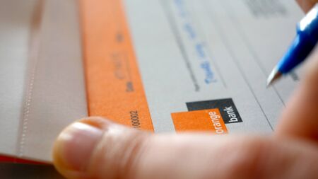 Paris, France - April 7, 2019: 2019: woman hands signing a banking check in the check book of Orange Bank - a bank by French telecom giant and Groupama insurance company 4k UHDのeditorial素材