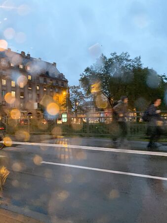 View through the rainy windshield of a car at the unrecognizable pedestrians walking on a cold fall day in central Strasbourgの写真素材