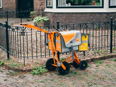 Haarlem, Netherlands - Aug 18, 2018: Orange mail transportation carriage device used by Post NL mail, parcel and e-commerce corporation with operations in the Netherlands, Germany, Italy, Belgiumのeditorial素材