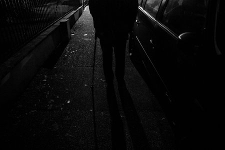 Black and white scene of Silhouette of senior man walking on French street at night using walking...