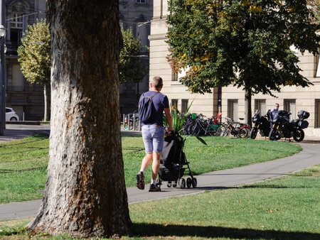 Strasbourg, France - Sep 21, 2019: Rear view of young man pushing baby pram on a French street