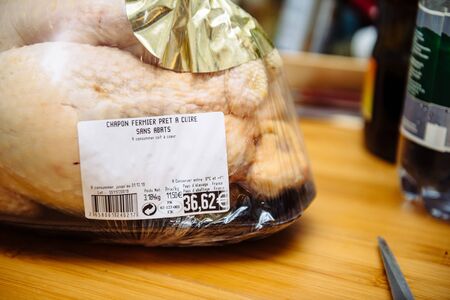 Paris, France - Dec 24, 2019: Price tag of 36,62 Euros on the packaging of fresh Capon Chapon cockerel meat on kitchen wooden topのeditorial素材