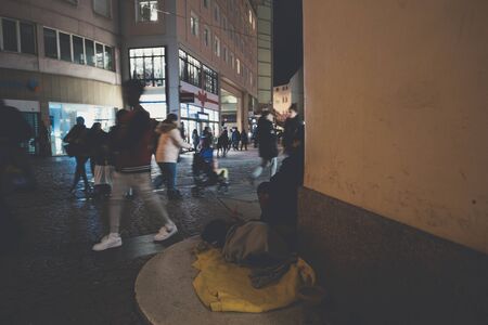 Strasbourg, France - Dec 24, 2018 Faded image effect over Defocused pedestrians silhouettes walking near the beggar man with dog on corner of the central French streetのeditorial素材
