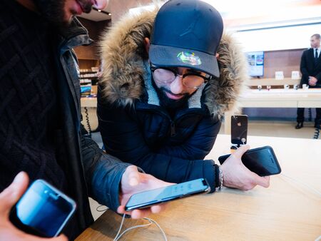 Paris, France - Nov 3, 2017: Curious male customers admiring inside Apple Store the latest professional iPhone 11 pro smartphone manufactured by Apple Computersのeditorial素材