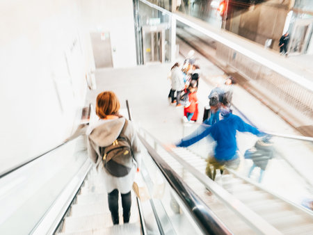 Defocused view with blur silhouettes of people on escalator and metro platform inside Barcelona...