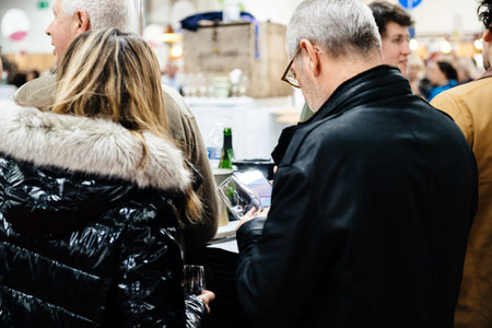 Strasbourg, France - Feb 16, 2020: Man holding wine glass and smartphone at the Vignerons...