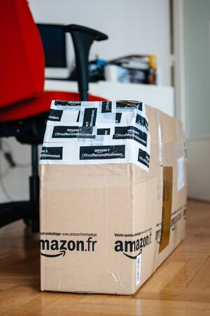London, United Kingdom - Feb 28, 2014: New parcel on parquet wooden floor from Amazon France parcel Warehouse deals - offre reconditionnees wrapped in multiple scotch bandsのeditorial素材