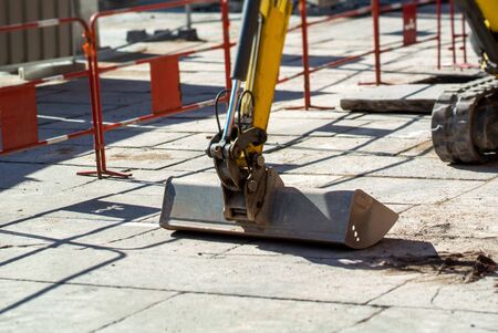 Small excavator bucket working on the large cobblestone stone plaques in central square of Strasbourgのeditorial素材