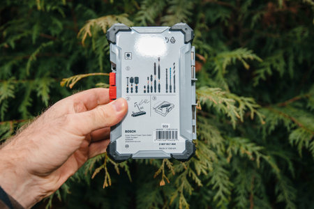 Paris, France - Feb 23, 2020: POV hand holding against green tree Arborvitae Thuya occidental of new package for Bosch professional cordless screwdriver accessories pick click set 40 piecesのeditorial素材