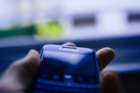 London, United Kingdom - Apr 21, 2013: Male hand holding in palm vintage Blackberry professional smartphone with focus on the logotype with the tilt-shift lensのeditorial素材