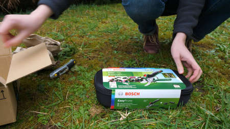 Paris, France - Mar 3, 2020: Woman unboxing unpacking Amazon cardboard parcel containing Bosch Cordless secateurs EasyPruneのeditorial素材