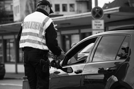 Kehl, Germany - Mar 16, 2020: Rear view of officer of the Federal Police checks traffic at the border crossing in Kehl from France Strasbourg during crisis measures in the fight against coronavirusのeditorial素材