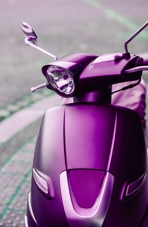 Front view of new electric scooter moped parked in a city - magenta color cast and defocused backgroundの写真素材
