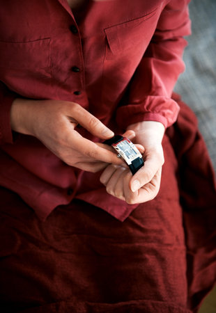 One woman in red robe testing hands holding luxury golden with red leather strap