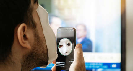 Paris, France - Nov 10. 2017: Close-up of Face Obstructed message on display of new Apple iPhone XS Pro with Face ID virtual facial recognition function with anonymous hacker wearing a maskのeditorial素材