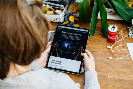 Paris, France - Apr 16, 2020: Binge worthy advertising for new iPhone SE as woman holds read on Apple Computers internet website on iPad Pro tablet in room environmentのeditorial素材