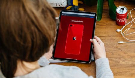 Paris, France - Apr 16, 2020: Comes in paw pdroduct red message - Woman looking on Apple Computers internet website on iPad Pro tablet in room environment showcasing new iPhone SEのeditorial素材