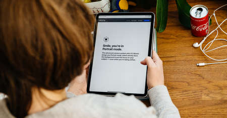 Paris, France - Apr 16, 2020: Smile yo're in portrait mode message as woman reads on Apple Computers internet website on iPad Pro tablet in room environment showcasing new iPhone SEのeditorial素材