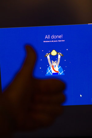 Paris, France - Mar 28, 2020: Man hand thumb up in front of computer monitor display with All Done...