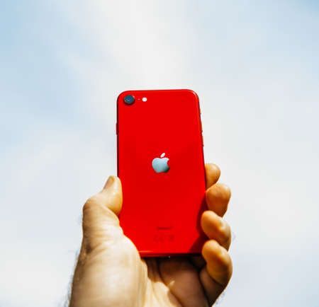Paris, France - Apr 24, 2020: Man rising to blue sky background new budget iPhone SE by Apple Computers touch ID, Single-lens rear camera and iPhone 8 design with internals from 11 Pro versionのeditorial素材