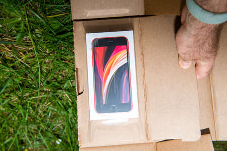 Paris, France - Apr 24, 2020: Man performing unboxing unpacking of new budget iPhone SE by Apple Computers touch ID, Single-lens rear camera and iPhone 8 design with internals from 11 Pro versionのeditorial素材