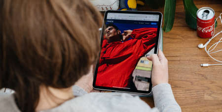 Paris, France - Apr 16, 2020: Advertising for photo camera on the new iphone SE as woman reads on Apple Computers internet website on iPad Pro tablet in room environment showcasing new iPhone SEのeditorial素材