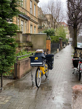 Strasbourg, France - Mar 5, 2020: View of La Poste French postal service delivery bike parked on empty street on a rainy dayのeditorial素材