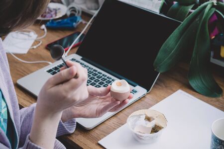 Side view of a lonely woman working from home eating a boiled egg during her teleworking session - worldwide epidemy of Coronavirus COVID19 has put people in lockdown and tele workingの写真素材
