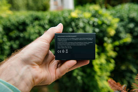 Paris, France - Aug 1, 2019: Male hand holding package with Made in China text of new Amazon smart plug working with Alexa personal assistant - green nature backgroundのeditorial素材