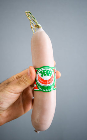 Paris, France - June 3, 2020: POV male hand holding against blue background delicious JECA Saucisse de foie et du jambonのeditorial素材