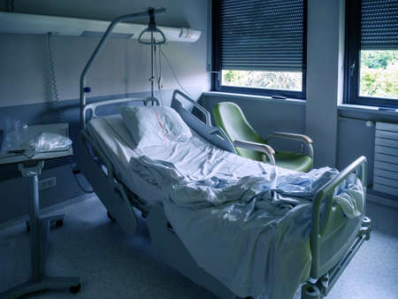 Empty hospital ward bed with blinds on windows inside the modern hospital recovery roomの写真素材